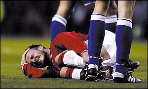 David Beckham grimaces and holds his foot after being fouled
